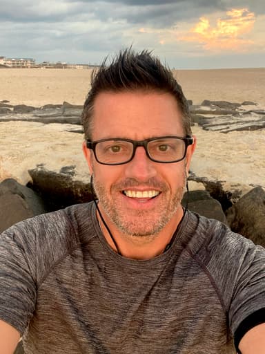 Rob Scott smiling at the beach during sunset, relaxed and happy