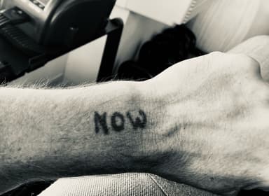 Rob Scott's NOW tattoo on his wrist, representing presence and the end of searching