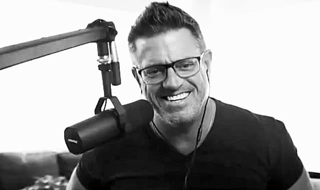 Rob Scott smiling during a podcast recording, wearing headphones